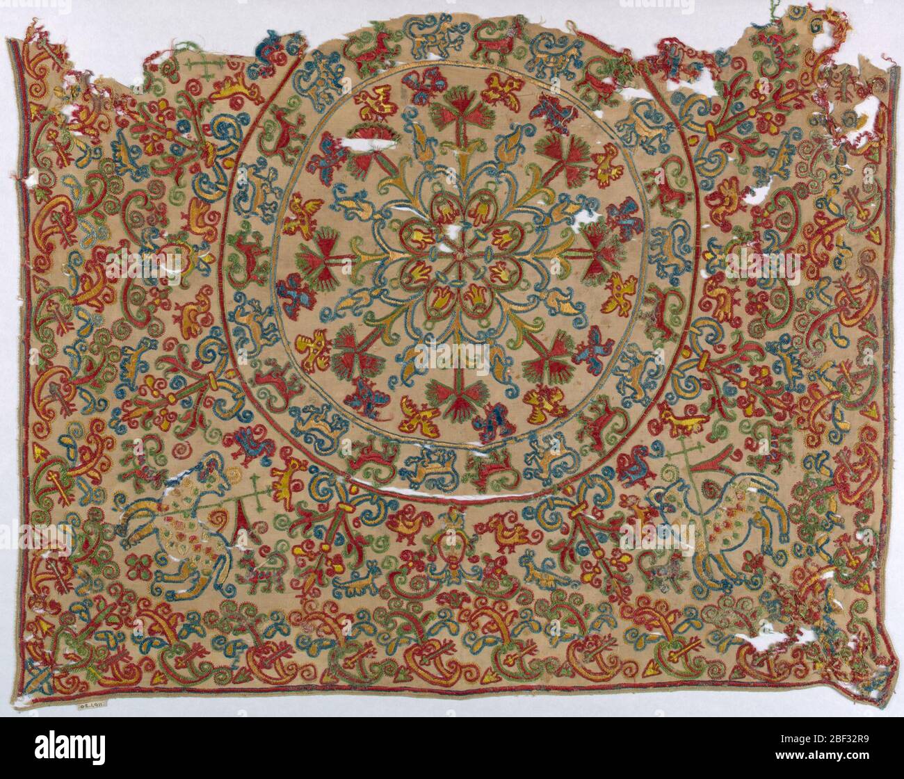 Velo di calice. Frammento di lino quadrato ricamato in tan, blu, rosso e verde. Stella centrale con rami radianti di garofani, boccioli di rose e uccelli, processione di animali. In angoli Agnus dei e Sacro cuore. Foto Stock