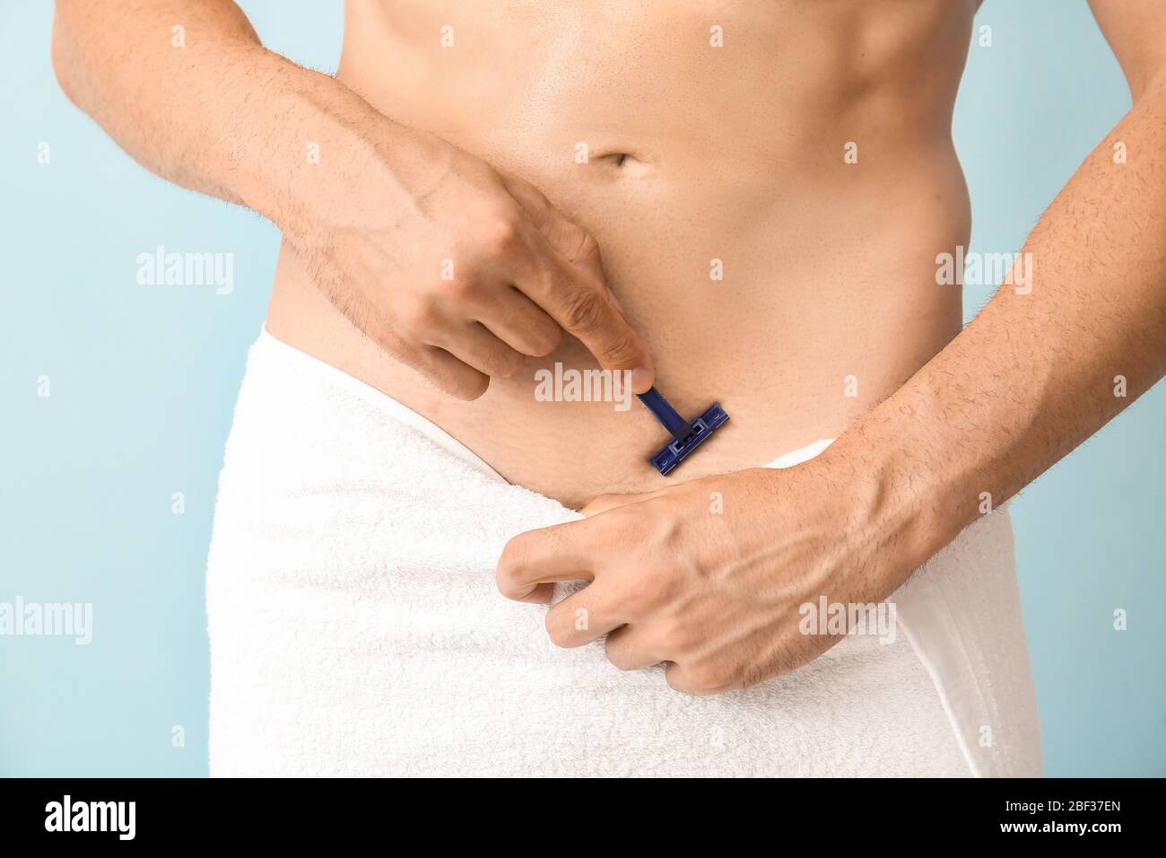 Bel giovane uomo radere il suo corpo su sfondo colorato, closeup Foto Stock