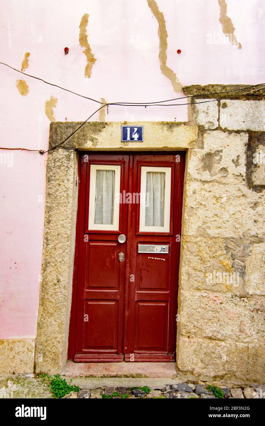 Piccola porta rossa con tende in pizzo nel quartiere Alfama di Lisbona Foto Stock