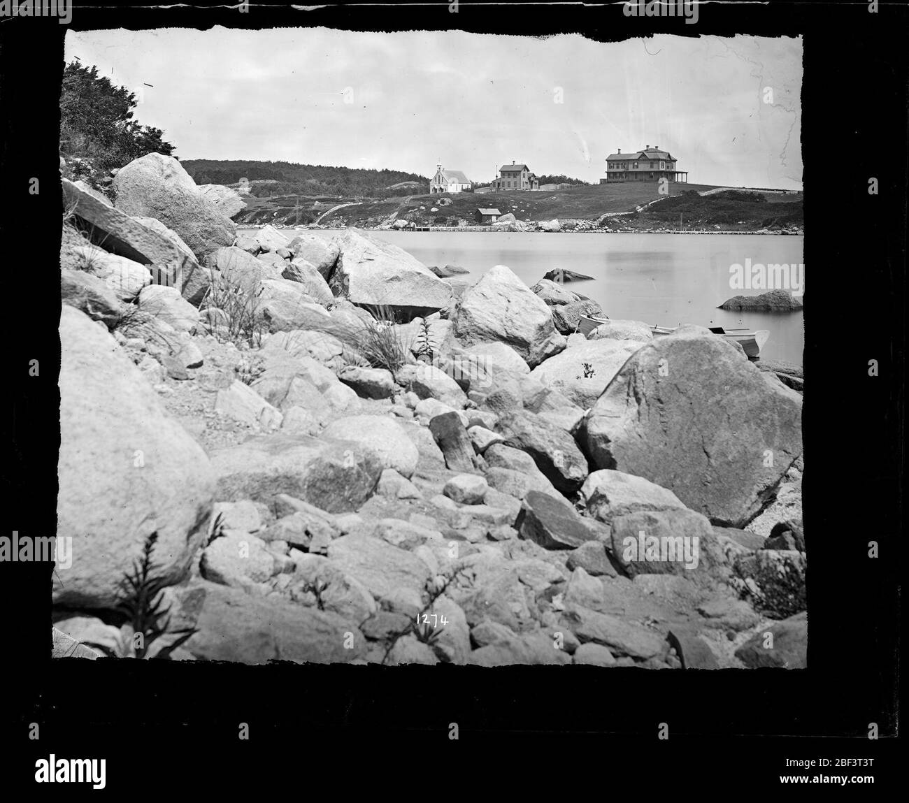 Woods Hole, Massachusetts. Costine rocciose di corpo d'acqua non identificato con case sullo sfondo. Woods Hole, Massachusetts.Smithsonian Institution Archives, ACC. 11-006, riquadro 001, immagine n. Foto Stock