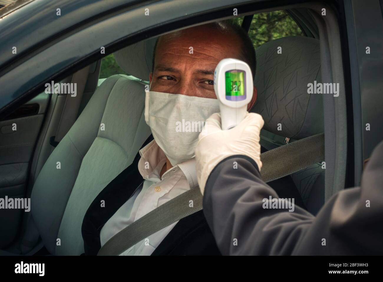 Colpo di poliziotto che misura la temperatura corporea di un adulto anziano sano con termometro a infrarossi nella sua auto Foto Stock