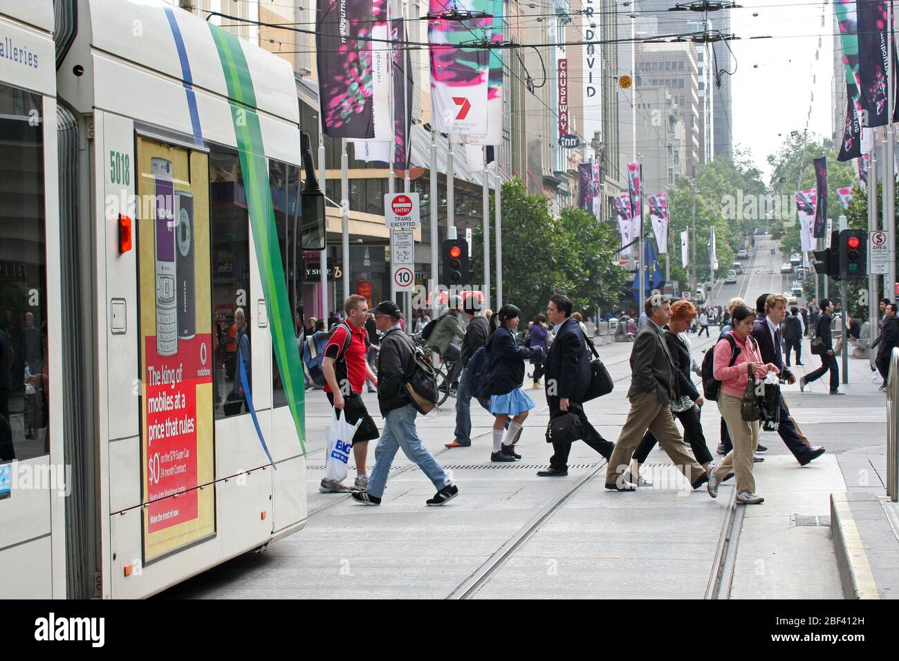 AMMIRA LA CITTÀ INTERNA DI MELBOURNE STREET, MOSTRANDO LA GENTE CHE ATTRAVERSA LA STRADA DOPO CHE È PASSATO UN TRAM. VICTORIA, AUSTRALIA. Foto Stock