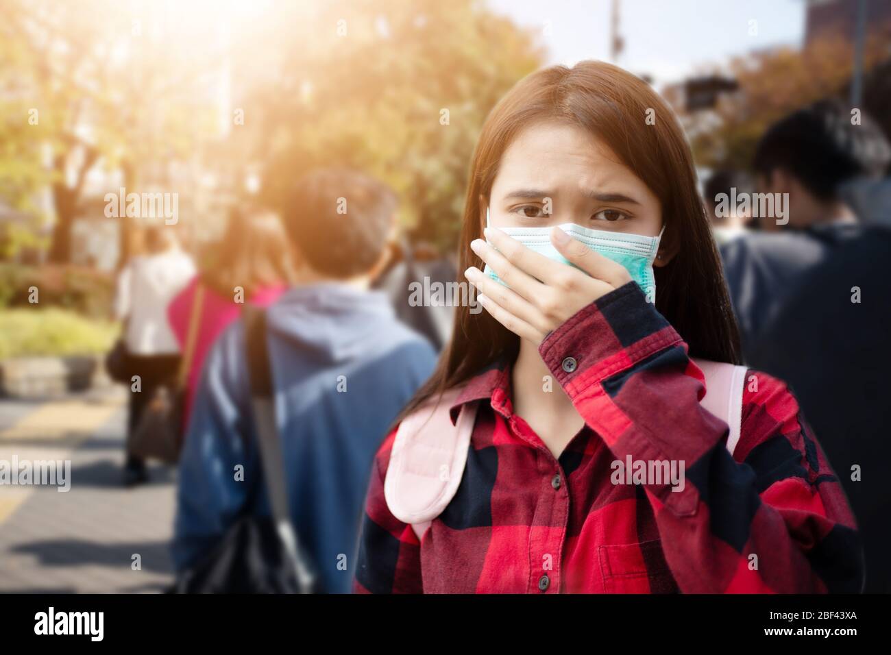 Giovane donna asiatica che cammina in città indossando maschera di protezione sul viso a causa dell'inquinamento atmosferico, particolato e per la protezione del virus influenzale, influenza, Foto Stock