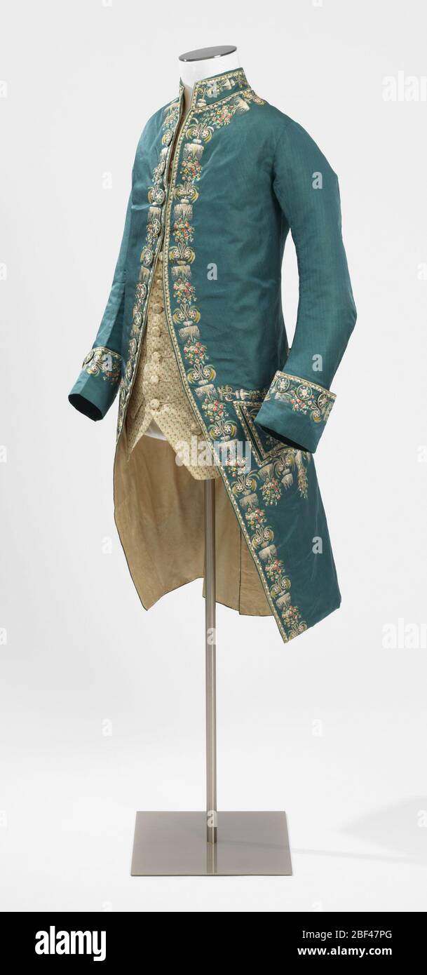 Cappotto. Cappotto di seta blu e verde mutevole con colletto, polsini, tasche e aperture anteriori e posteriori ricamate con morbidi sete policrome in disegno di ghiaccioli con spray pendenti di minutissime pansies, margherite e pinks; alternate a monogramma 'I.C.', decorato con Foto Stock