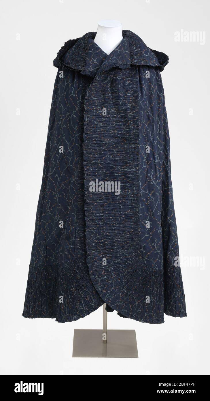 Capo. capo in cotone stampato da donna, aperto sul davanti, con un cappuccio con un ruffle pieghettato tutto intorno. Il tessuto è blu indaco scuro disegno scarico in azzurro, con tocchi di arancio. Foto Stock