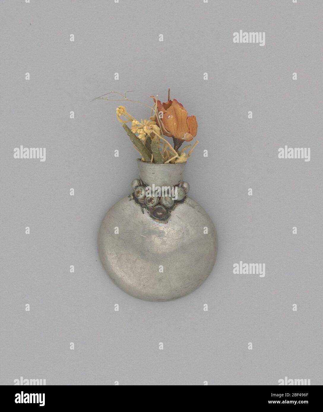 Bouquet perno vaselizzato più vecchio. Perno portamazzo pewter piccolo. Il vaso è a forma di urna con perle intorno al collo. Il retro è piatto con perno per l'attacco di un indumento.i fiori utilizzati per il complementi personali sono stati un accessorio di moda popolare durante il 1800 fino alla metà del 1900. Foto Stock
