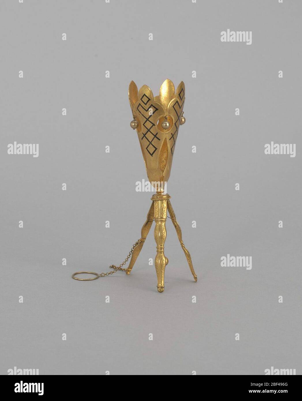 Palline per treppiede per bouquet. Questo supporto per bouquet per treppiede è formato in due sezioni. La parte superiore è realizzata con quattro pannelli in ottone dorato a forma di foglia stilizzata per creare il vaso. I pannelli sono separati da piccole aperture. Dai fori più in alto, un singolo cordone pende in ogni finestra. Foto Stock