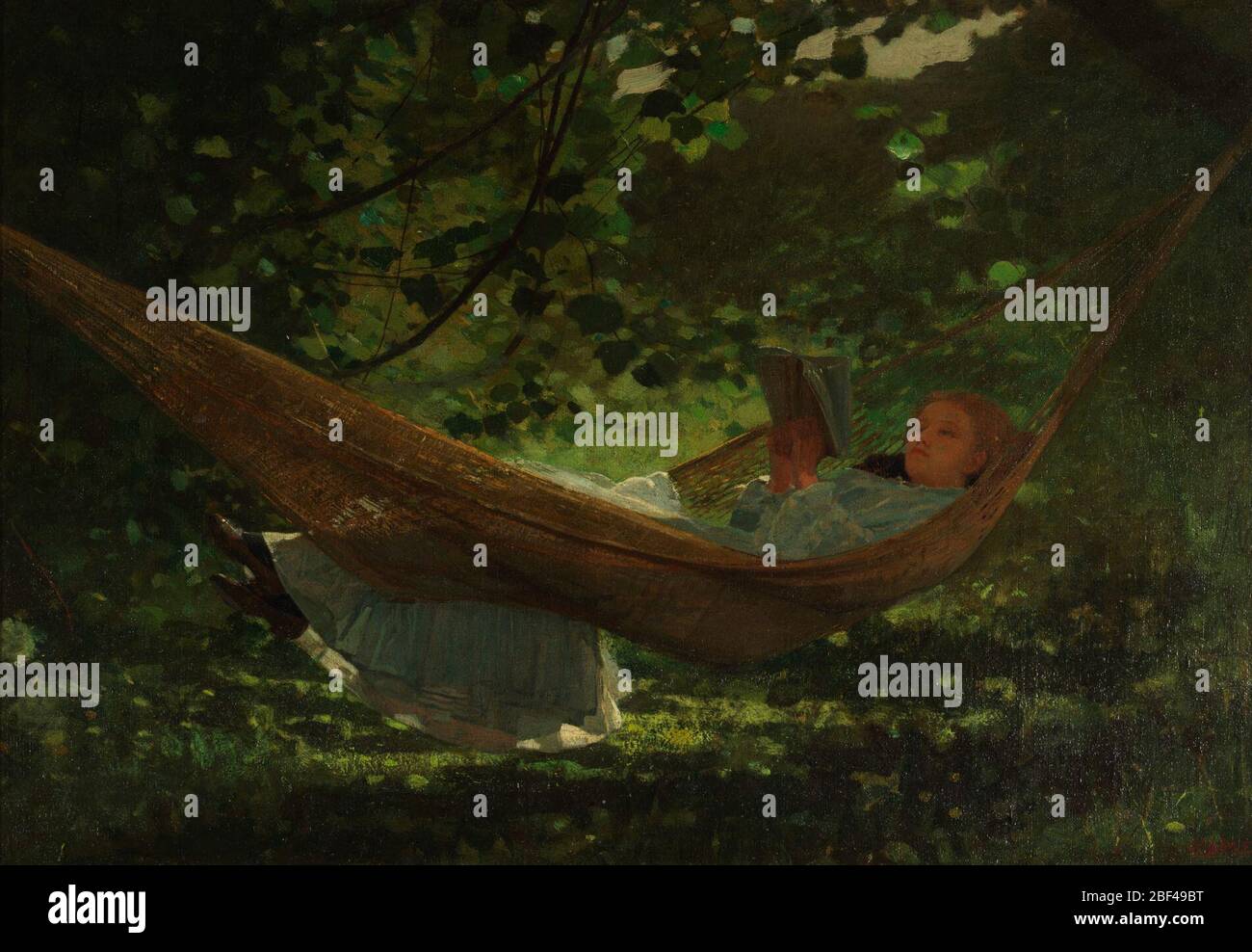 Luce del sole e ombra. Vista orizzontale di una giovane donna in un abito bianco, sdraiato in un'amaca con i suoi piedi sopra il bordo, leggendo un libro. È in un ambiente di alberi e erba appled alla luce del sole. Foto Stock