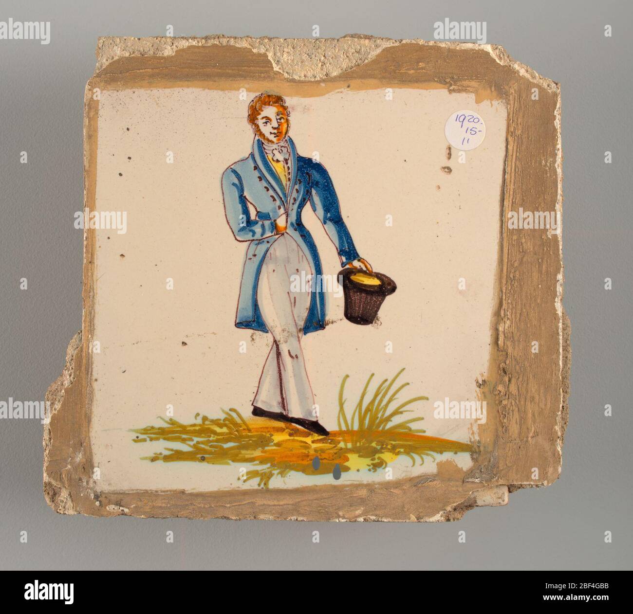 Affiancamento. Uomo con lunghi pantaloni bianchi e un breve cappotto blu che cammina verso destra e tiene un cappello nero sulla sua sinistra. Foto Stock