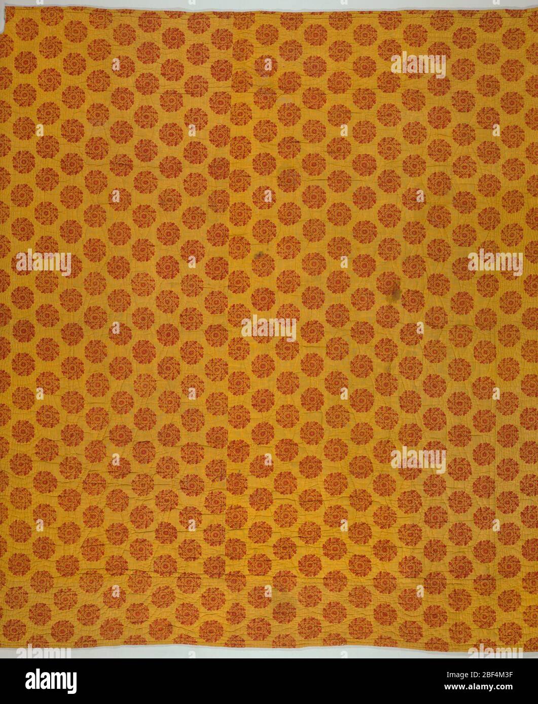 Trapunta. Trapunta un lato di cui è grande pezzo di primi 19 ° secolo rilievo-stampato tessuto con un modello tutto-su di una piccola rosetta in rosso su uno sfondo giallo in una mezza goccia ripetizione. Foto Stock
