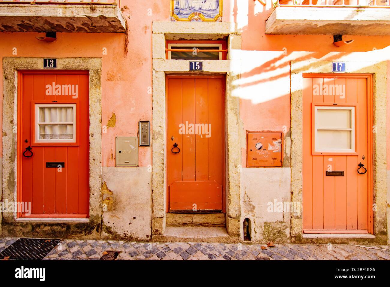 Tre porte arancioni dipinte in un edificio corallino nel quartiere Alfama di Lisbona Portogallo Foto Stock
