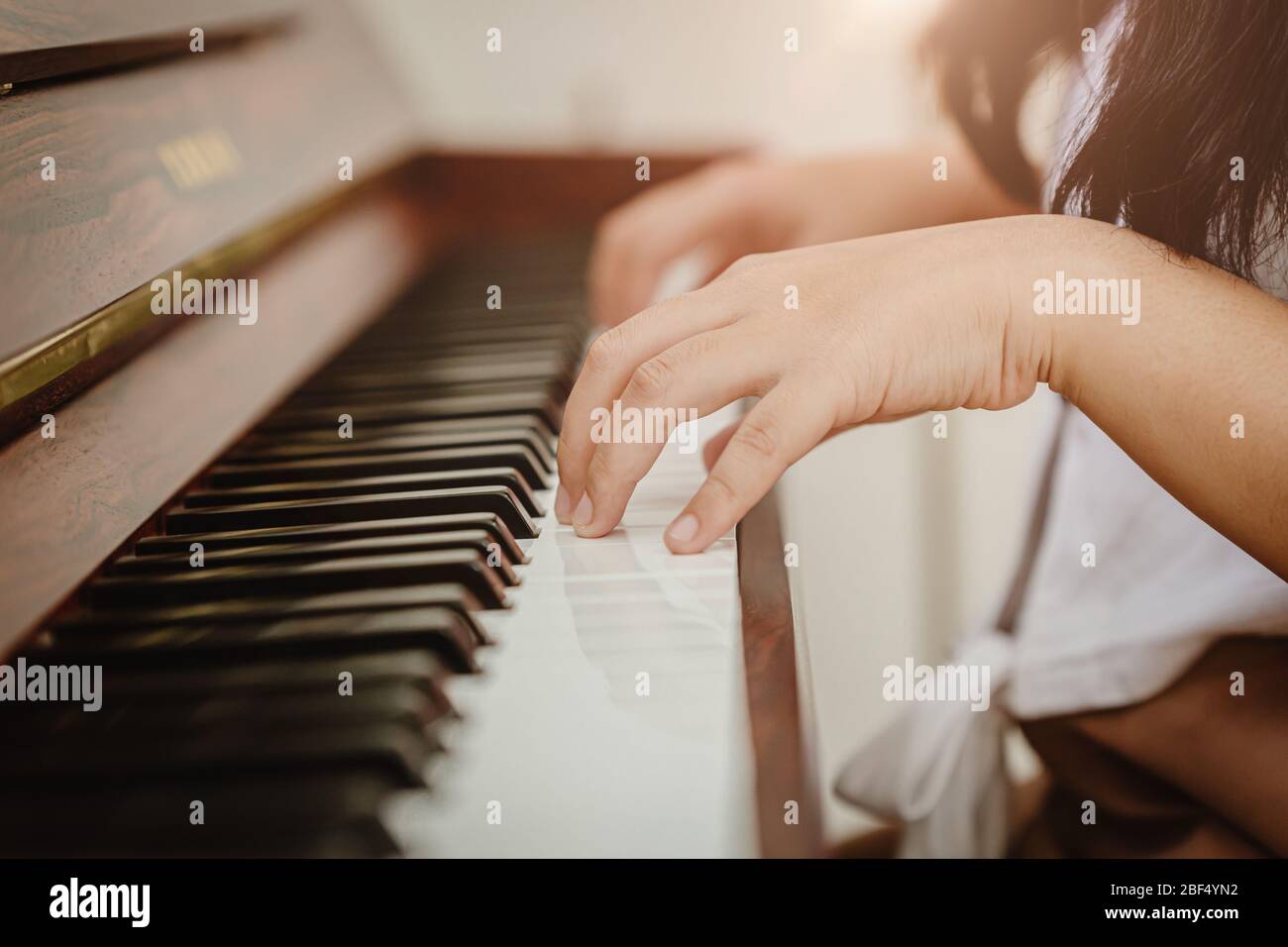 Closeup donna mano suonare piano a casa tonalità di colore vintage. Foto Stock