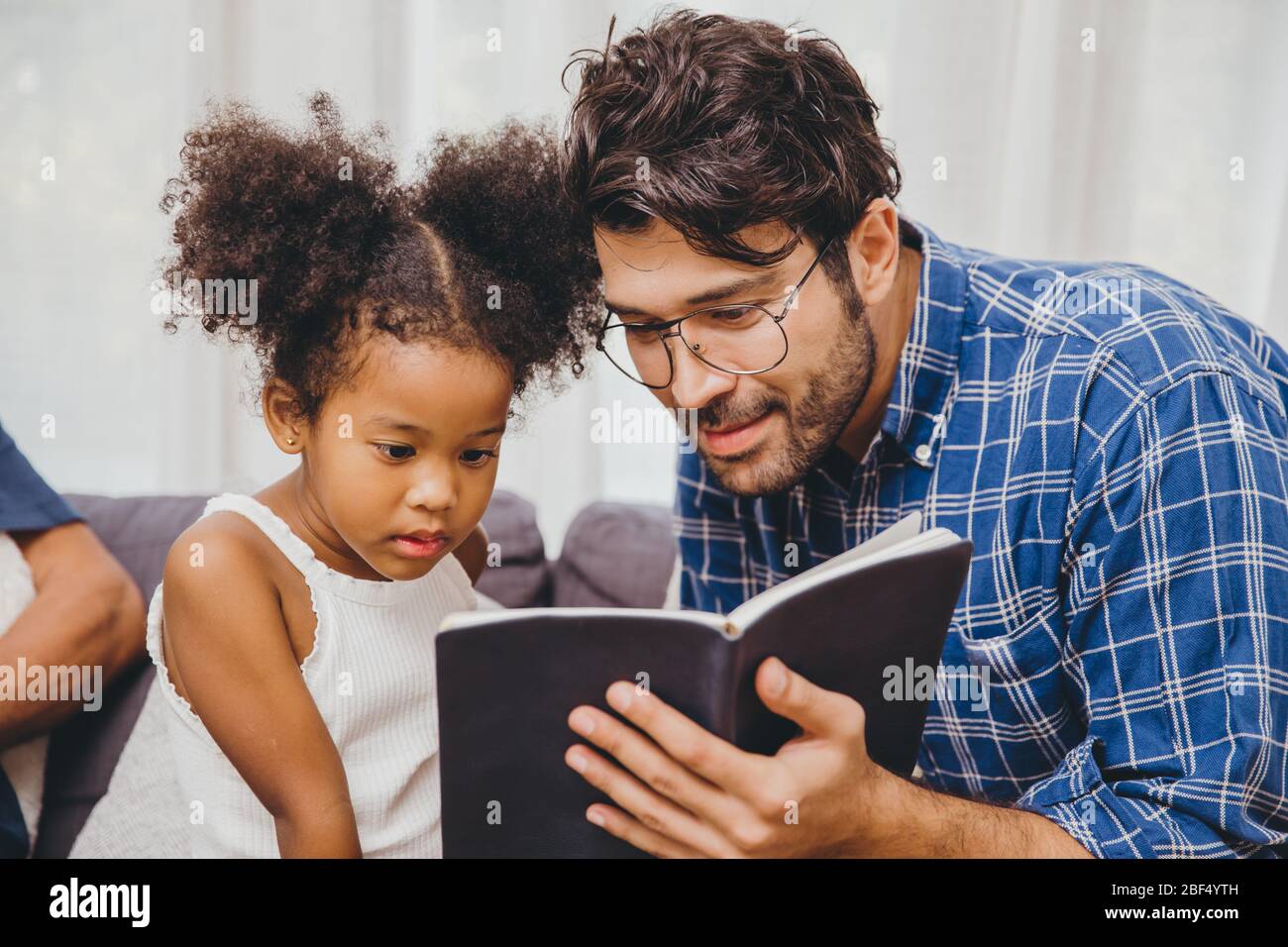 Bambino carino piccolo interessante l'amore del libro leggere ed imparare il supporto dal papà al concetto intelligente del capretto. Foto Stock