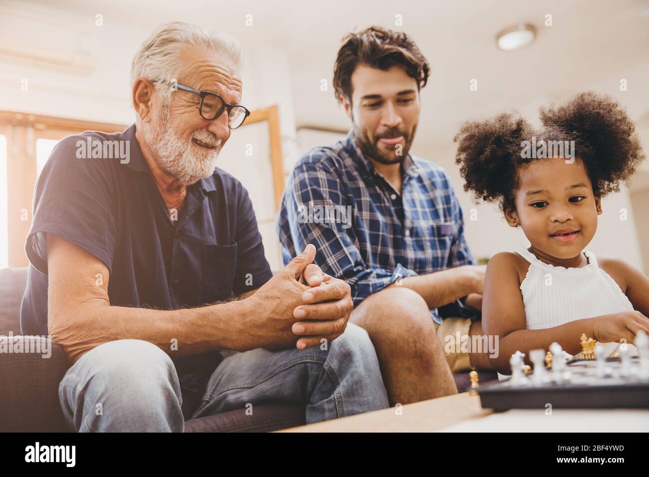 Felice famiglia momento anziano con bambino bambina e figlio a casa felicità momento giocando a scacchi gioco. Foto Stock