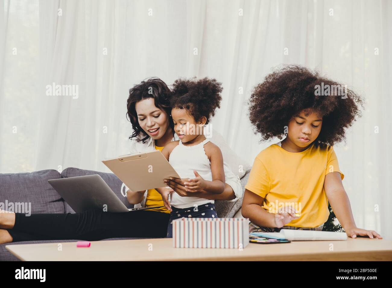 Il lavoro del genitore a casa da computer portatile del Internet effetto di covid-19 malattia pandemica del virus madre sana felice di vivere per rimanere e giocare con il suo chil Foto Stock