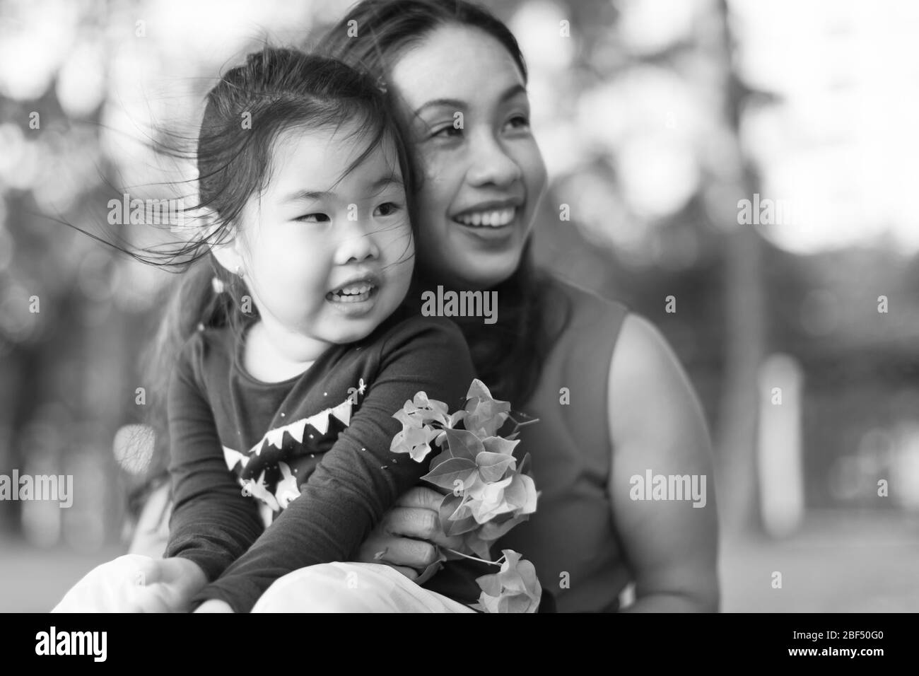Una bambina seduta sulle sue mamme lap al parco, godendosi il tempo insieme. Amore di famiglia. Foto Stock