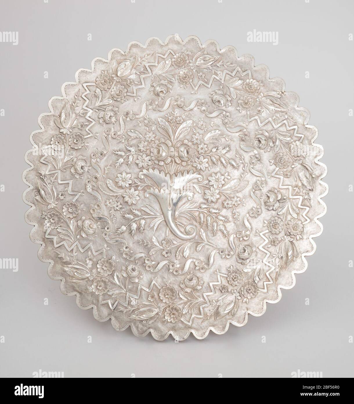 Specchio. Cornice in argento circolare smerlata impreziosita da foglie e fiori che reggono lo specchio. Rievocazione della schiena con corona floreale, con bouquet di corno in abbondanza al centro. Foto Stock