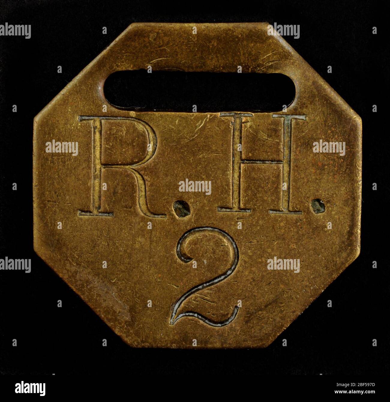 Etichetta Owney contrassegnata RH. Questa etichetta ottagonale in ottone è contrassegnata con le iniziali R.H. e il numero "2". Non sono disponibili informazioni per indicare quando questo tag è stato presentato a Owney, chi lo ha presentato o dove. Foto Stock