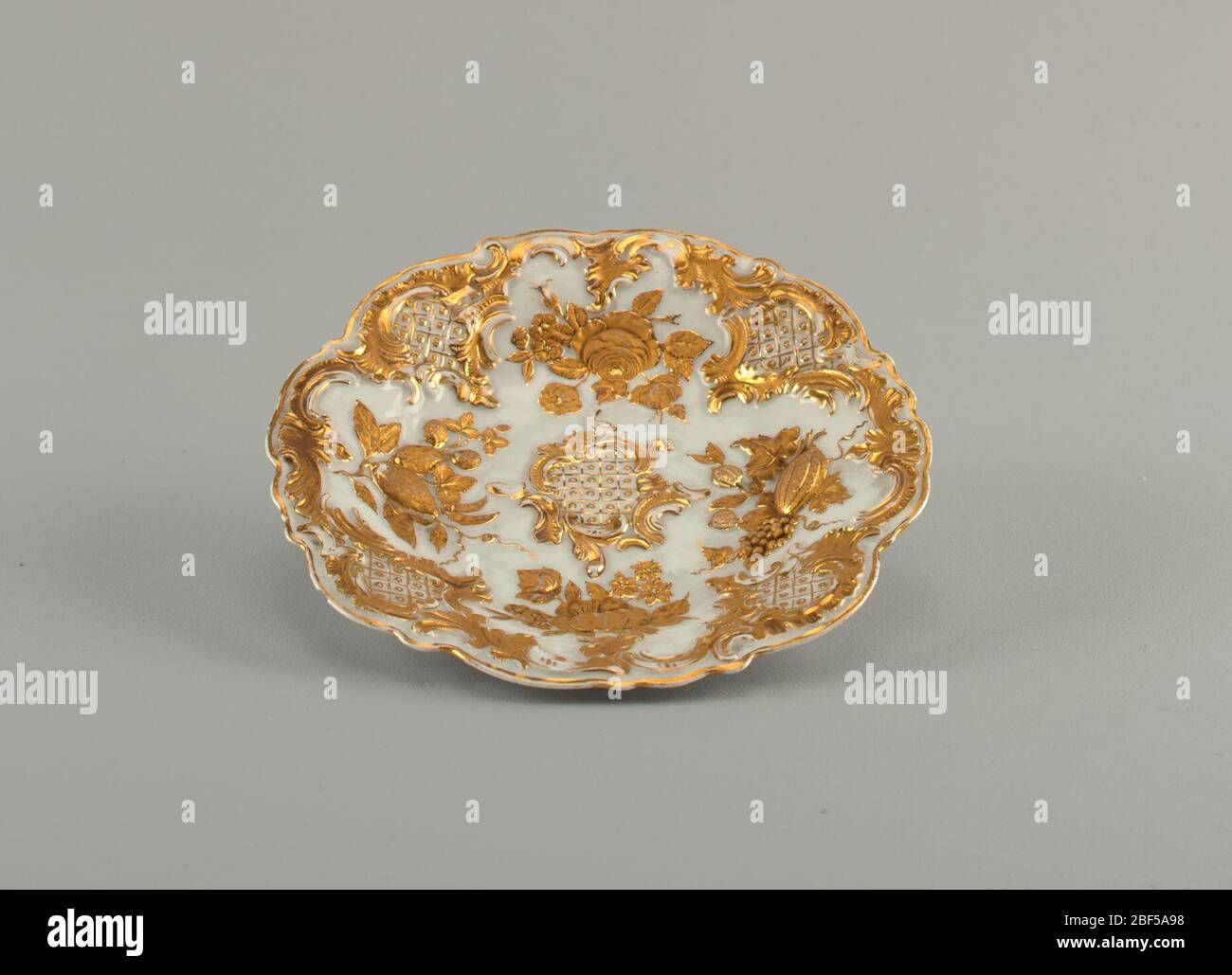 Piatto da dessert. Piatto ovale con bordi smerlati, parzialmente dorato con ornamento floreale in rilievo. Foto Stock
