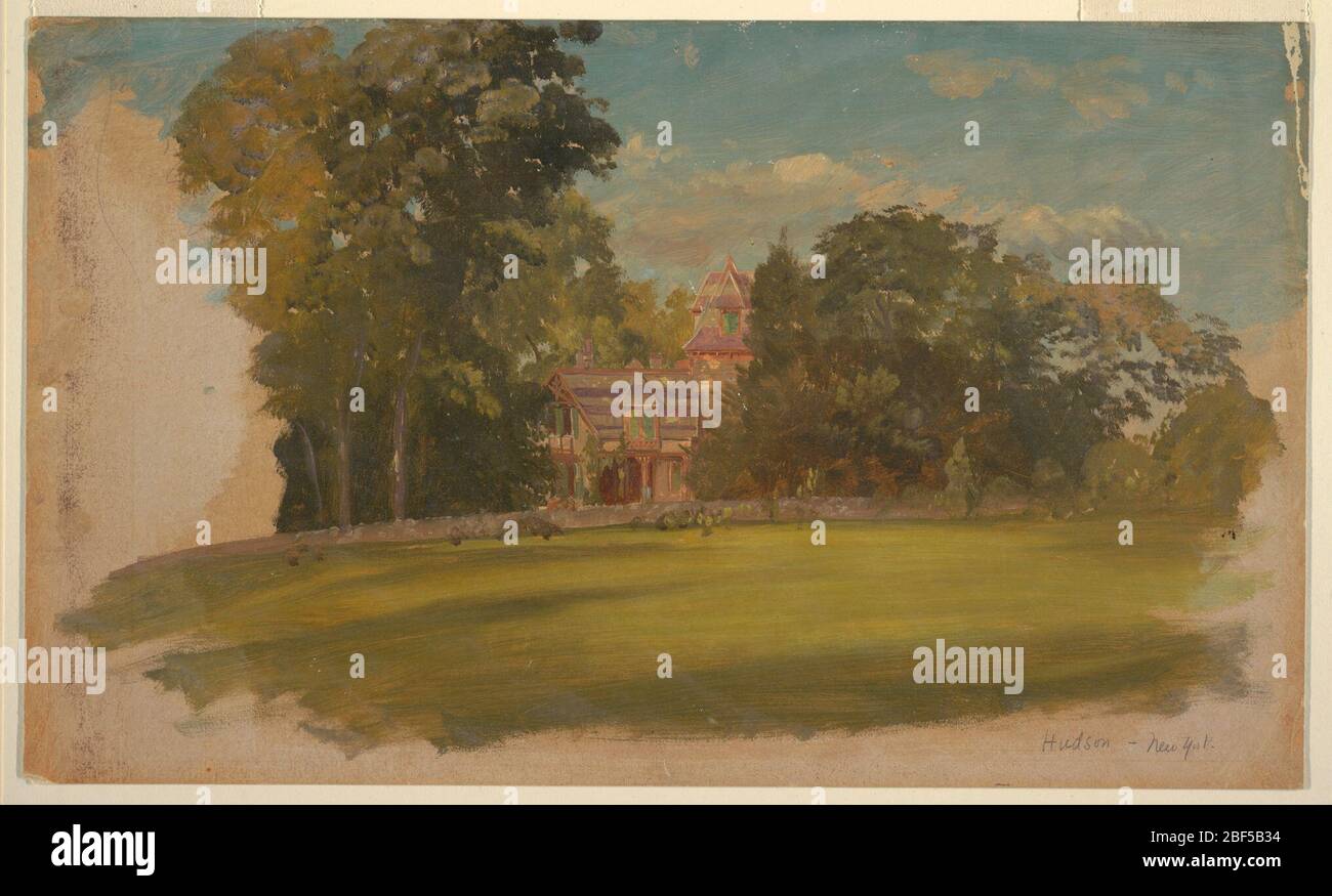 Casa a Hudson New York. Vista orizzontale di una casa con torre, al centro della distanza media, fiancheggiata da e di fronte agli alberi. In primo piano è un prato delimitato posteriormente da un basso muro di pietra. Il colore crema del terreno è visibile ai bordi inferiore destro e sinistro. Foto Stock