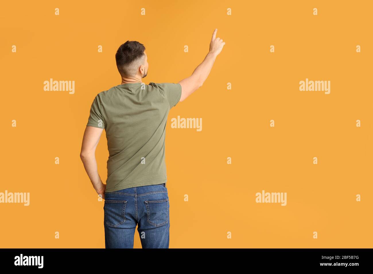 Uomo che punta qualcosa su sfondo a colori, vista posteriore Foto Stock