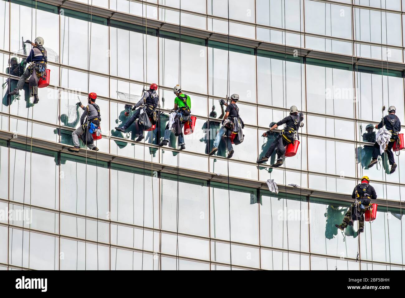 Alto edificio pulitrici per finestre al lavoro sulla facciata vetrata di un grattacielo a Milano Foto Stock