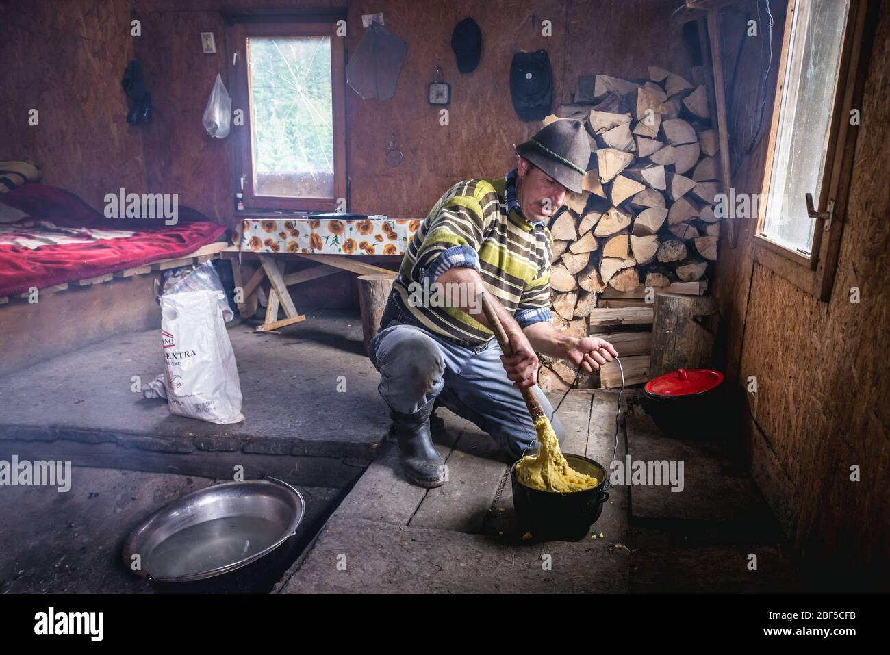 L'uomo prepara Mamaliga in una capanna di pastore di montagna in località di Borsa nelle montagne Rodna, che si trova nella Contea di Maramures della Romania del Nord Foto Stock