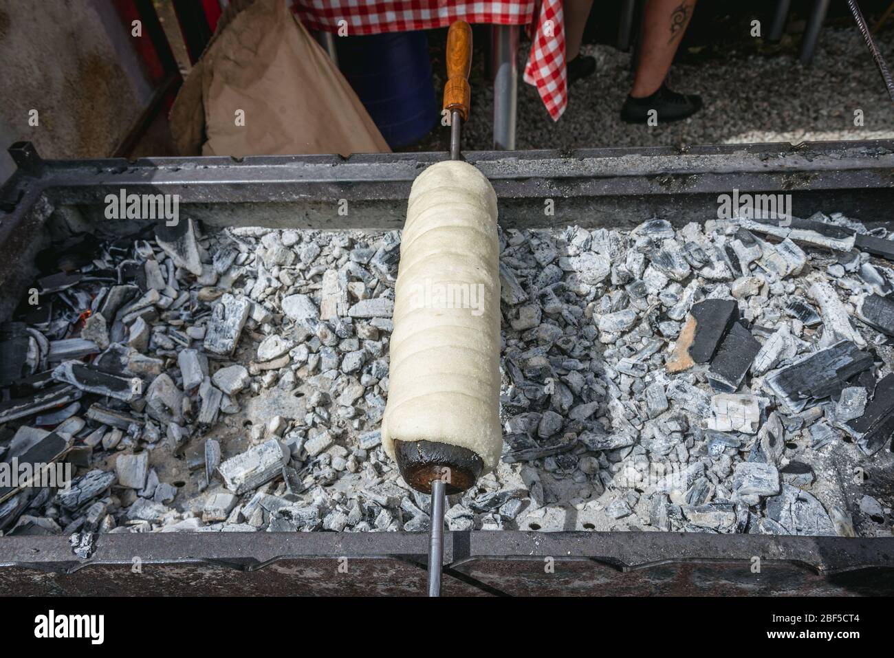 Cottura di torta di spit ungherese Kurtoskalacs in località di Borsa nelle montagne Rodna, situato nella contea di Maramures del nord della Romania Foto Stock
