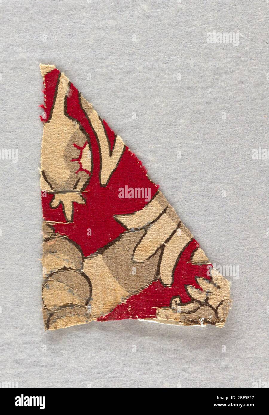 Frammento. Un piccolo frammento di tappezzeria figurata con dettagli di piante stilizzate su un terreno cremisi. Foto Stock