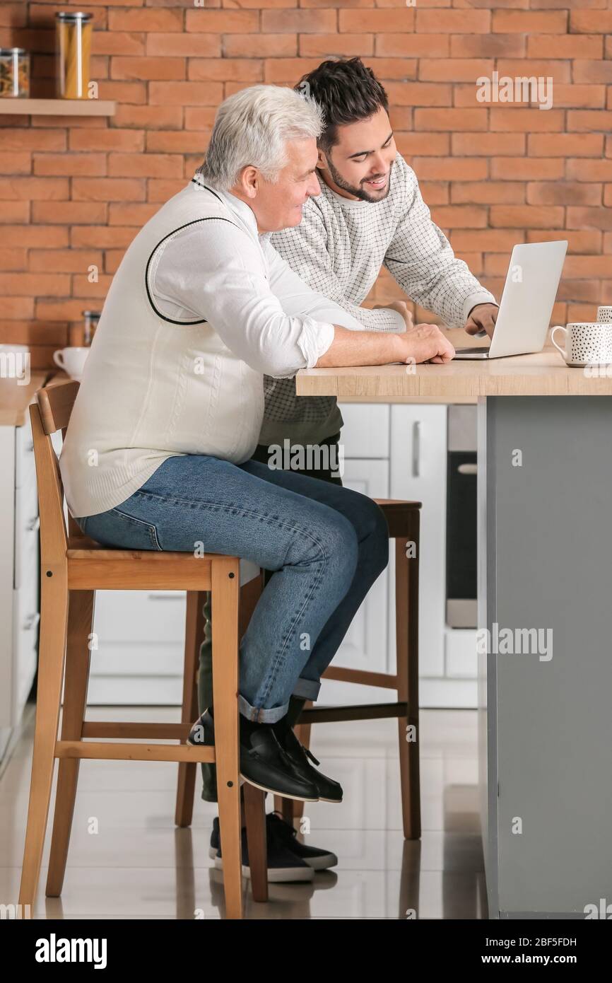Giovane e padre con computer portatile in cucina Foto Stock