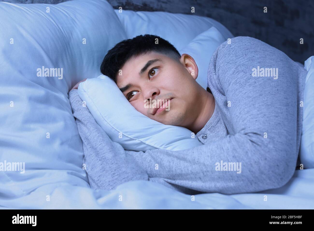 Uomo asiatico che soffre di insonnia di notte Foto Stock