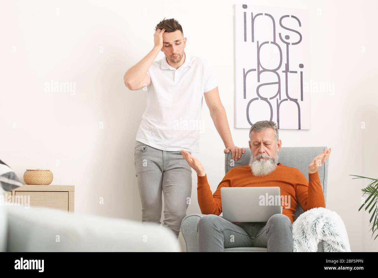 Giovane uomo che insegna al padre di gestire con un computer moderno Foto Stock