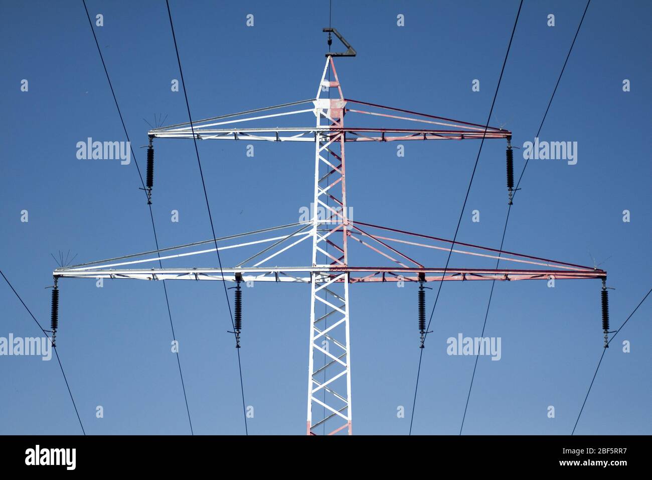 Un pilastro ad alta tensione che fornisce energia contro un cielo blu Foto Stock