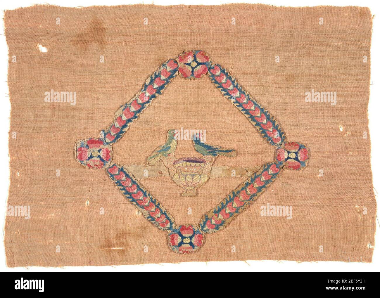 Frammento. All'interno di una cornice di cuori sovrapposti, due uccelli su ogni lato di una tazza o calice. Montato su un altro tessuto. Foto Stock