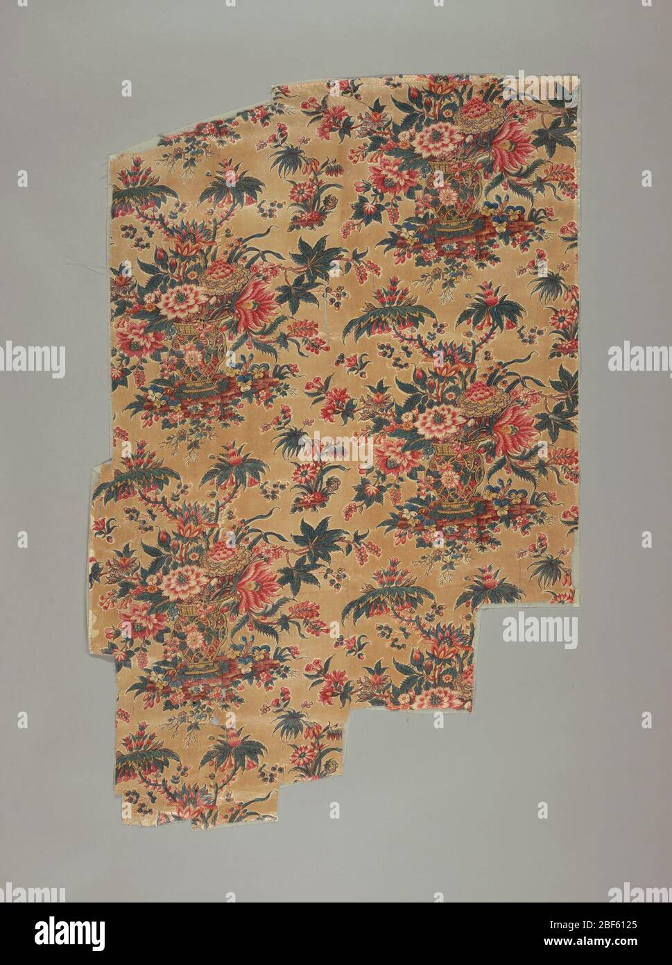 Tessile. Sull'abbronzatura chiara 'terra del tè' è una grande ripetizione di un vaso esotico contenente un mazzo elaborato di fiori fantasy stampati in rosso, giallo, blu e 'doppio verde' di blu stampato su giallo. Alta qualità di stampa. Foto Stock