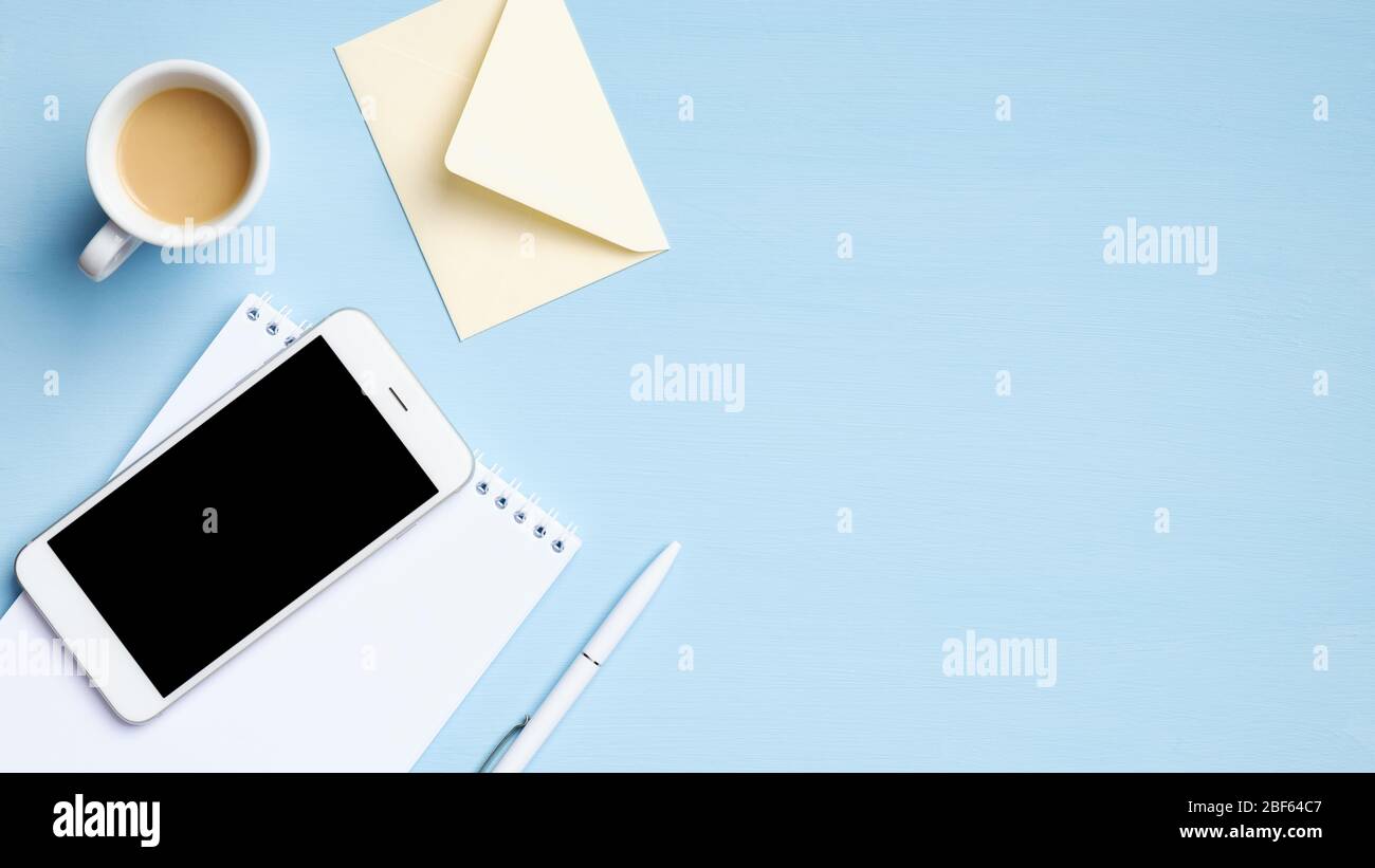 Scrivania da ufficio con smartphone con schermo vuoto, tazza di caffè, notebook, busta, penna. Disposizione piatta, vista dall'alto, spazio per la copia. Azienda c Foto Stock