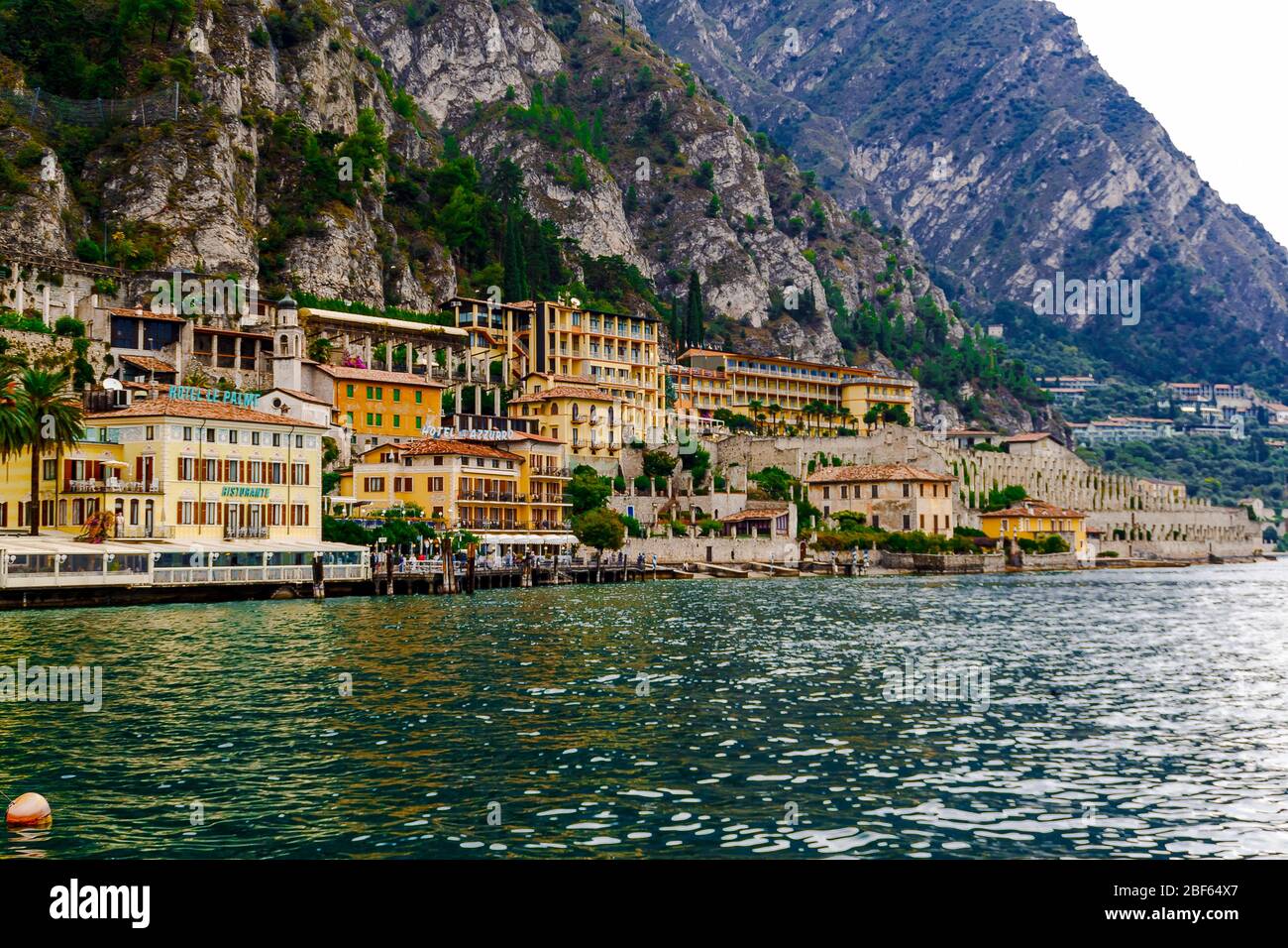 Limone sul Garda, Brescia / Italia - 24 settembre 2017: Case colorate e alberghi sulla riva del lago sullo sfondo delle montagne. Foto Stock