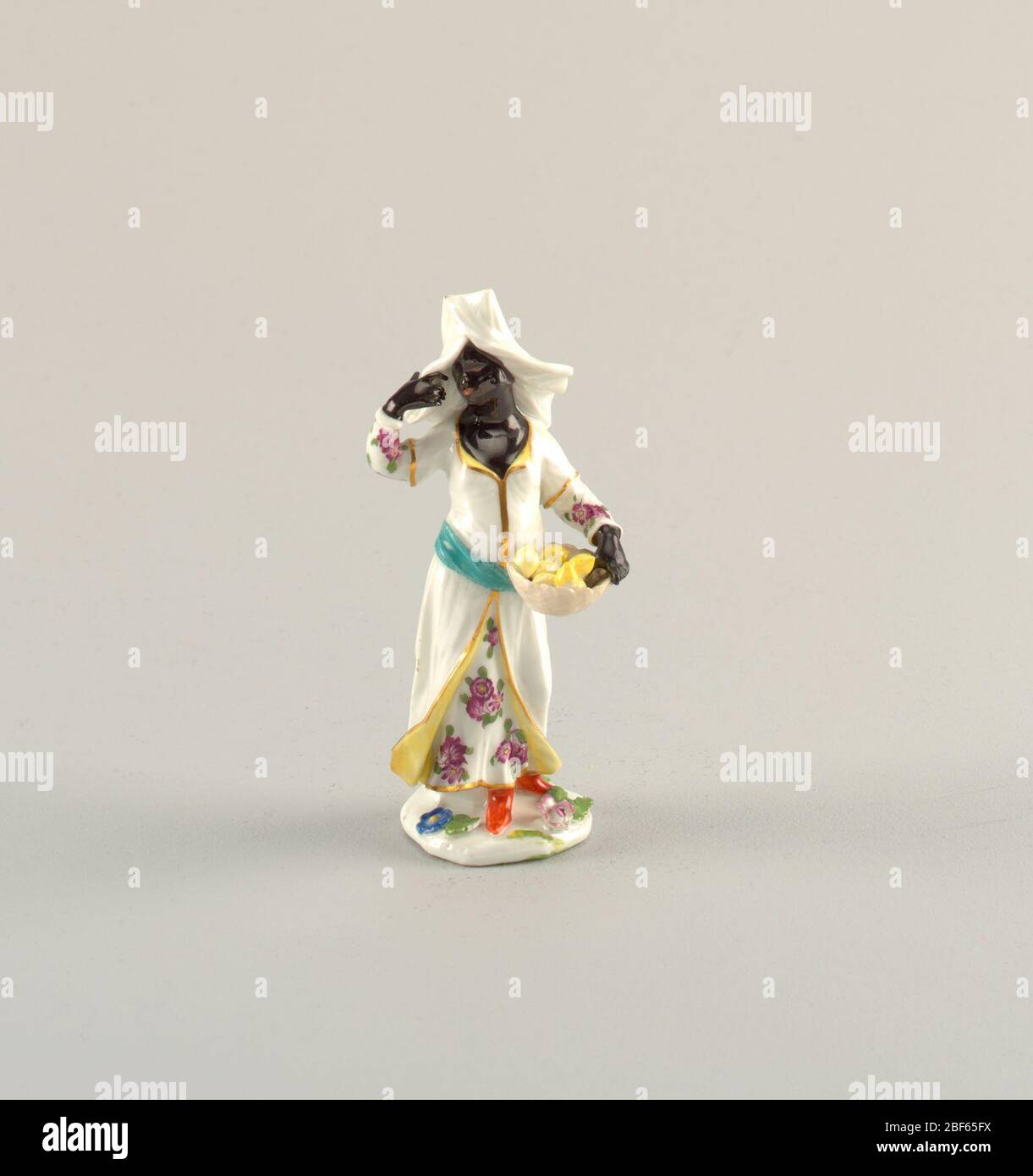 Blackamoor Figura di un Venditore di frutta e Blackamoor Figura di un Servant. a) femmina nera, con palpina, in headdress quadrato, che tiene un cesto di limoni; b) maschio nero turbinato con coppa coperta su tazza. Basato su modelli di circa 1740. Foto Stock