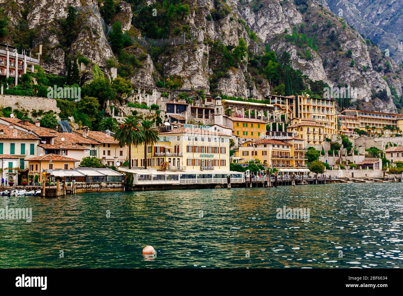 Limone sul Garda, Brescia / Italia - 24 settembre 2017: Case colorate e alberghi sulla riva del lago sullo sfondo delle montagne. Foto Stock