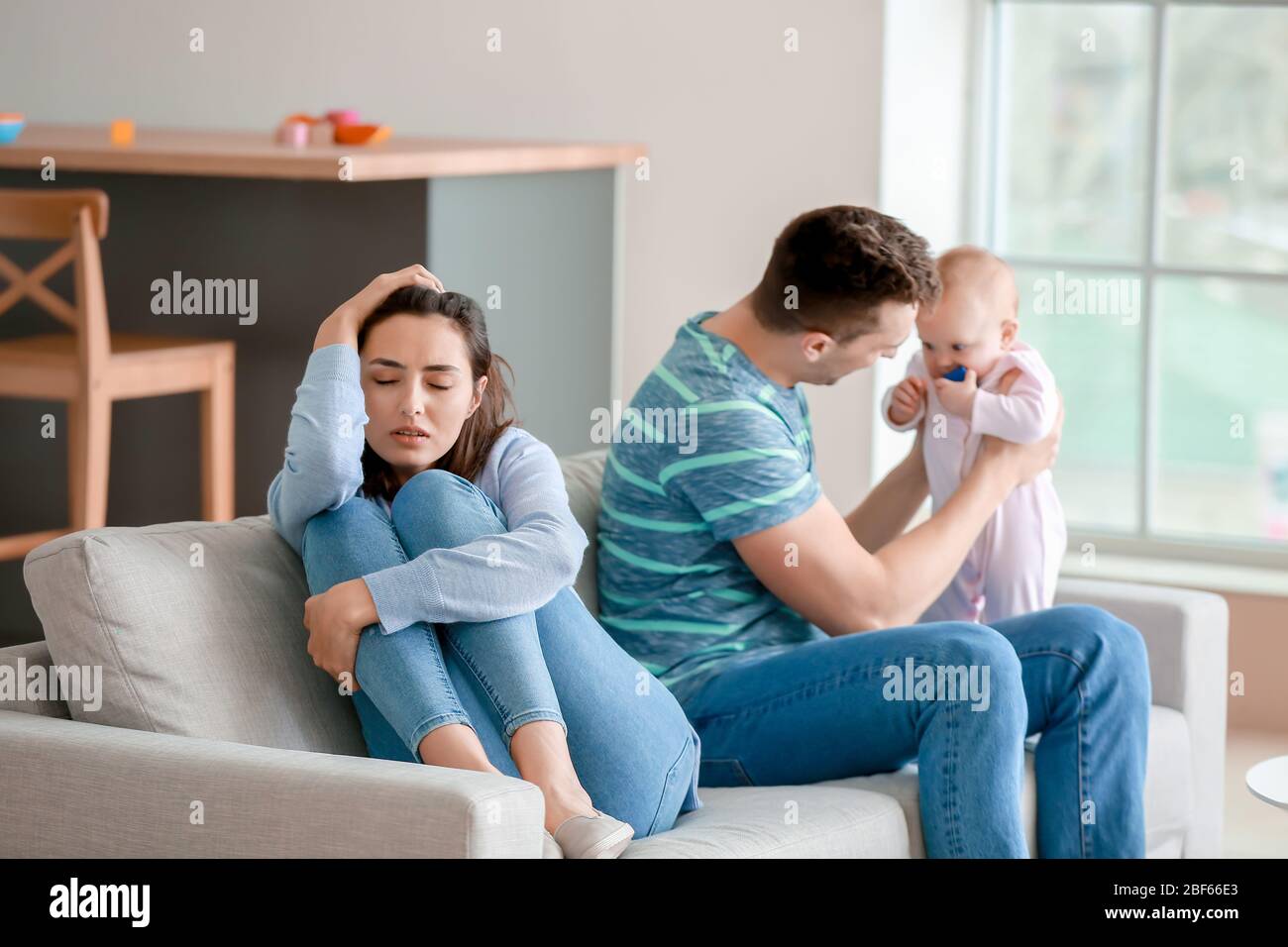 Buon padre con il suo bambino e la moglie che soffrono di depressione postnatale a casa Foto Stock