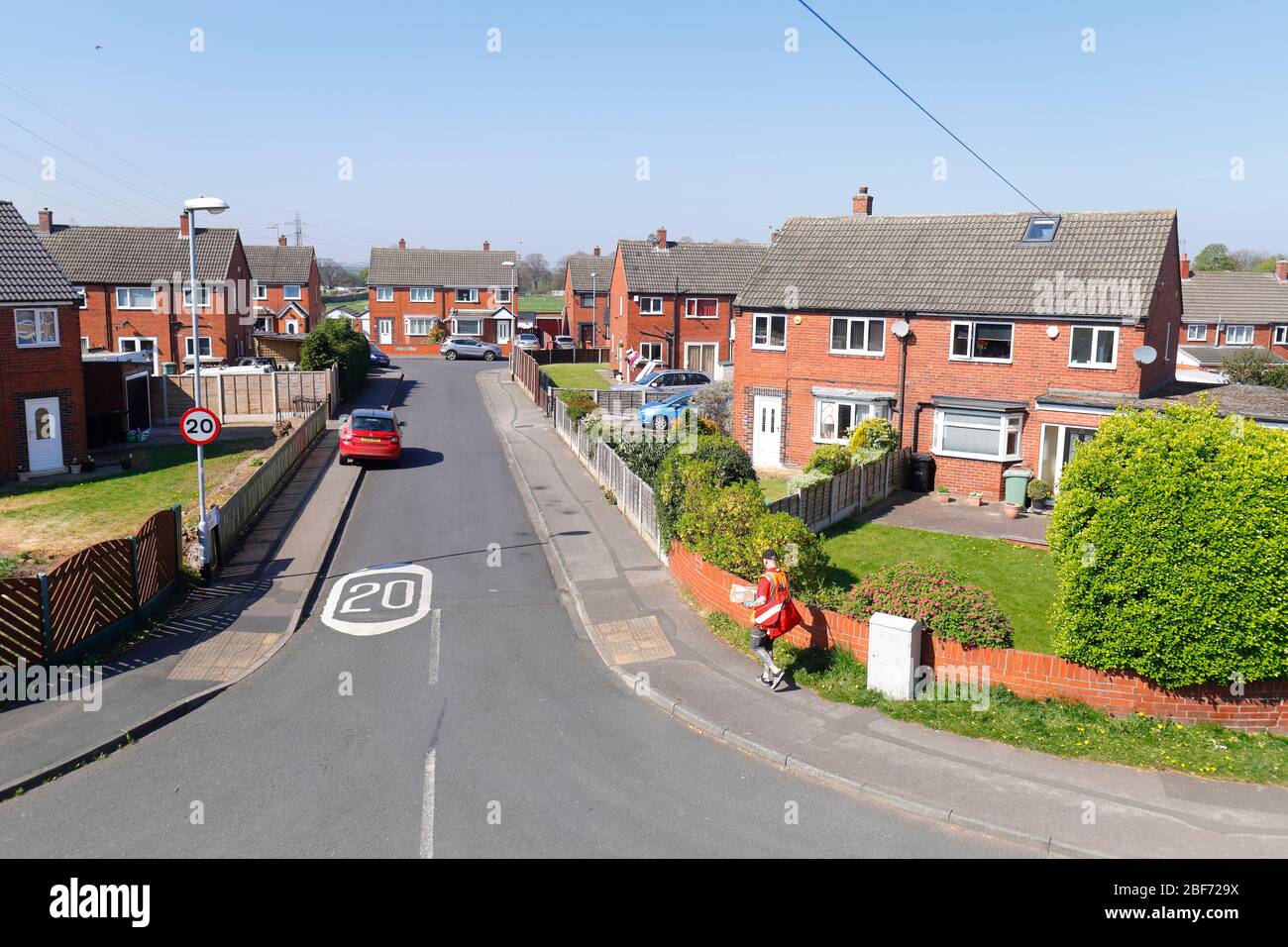 Un postino consegna la posta ai residenti di Park Grove a Swillington. Foto Stock