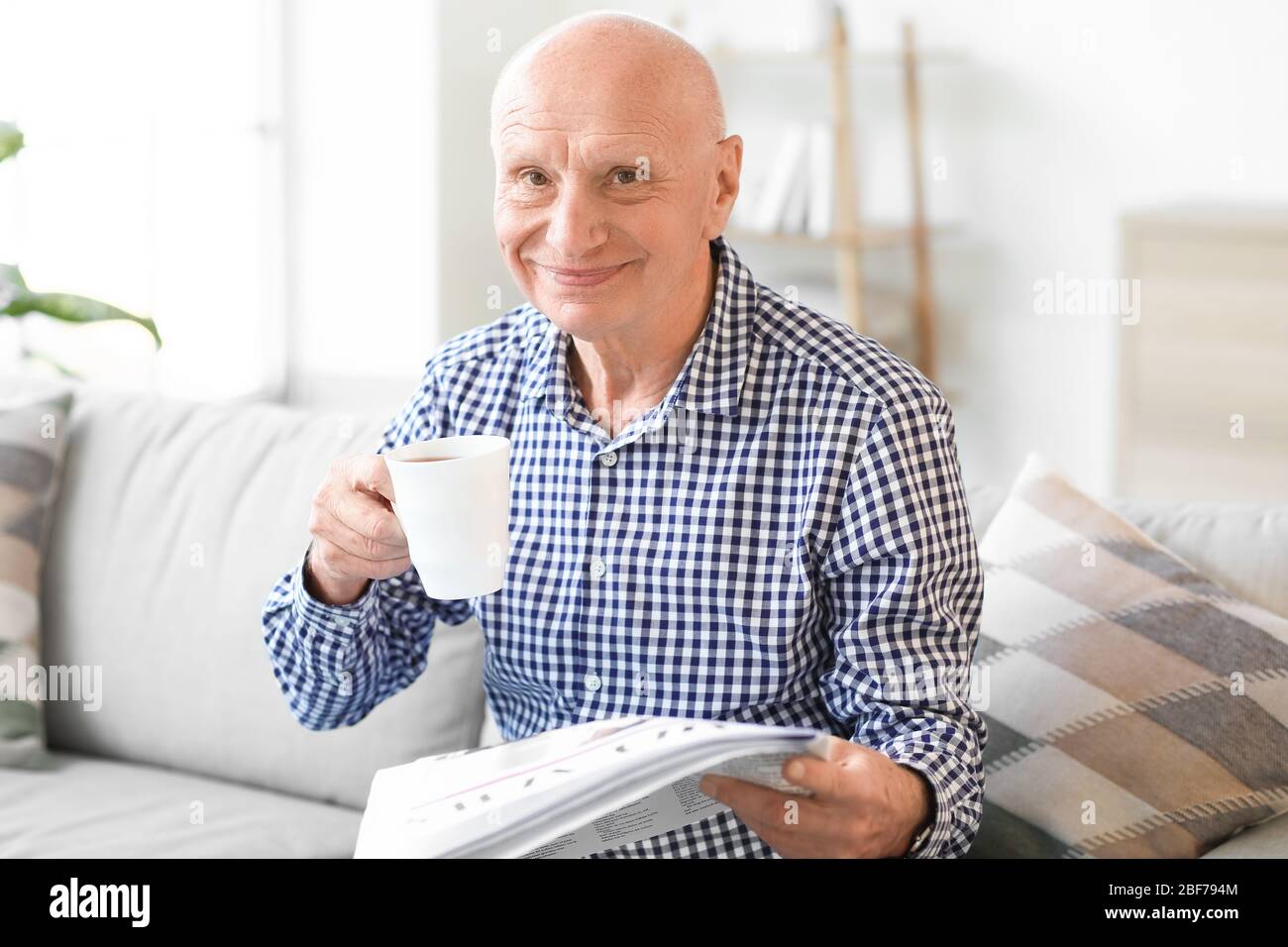 Uomo anziano che legge giornale a casa Foto Stock
