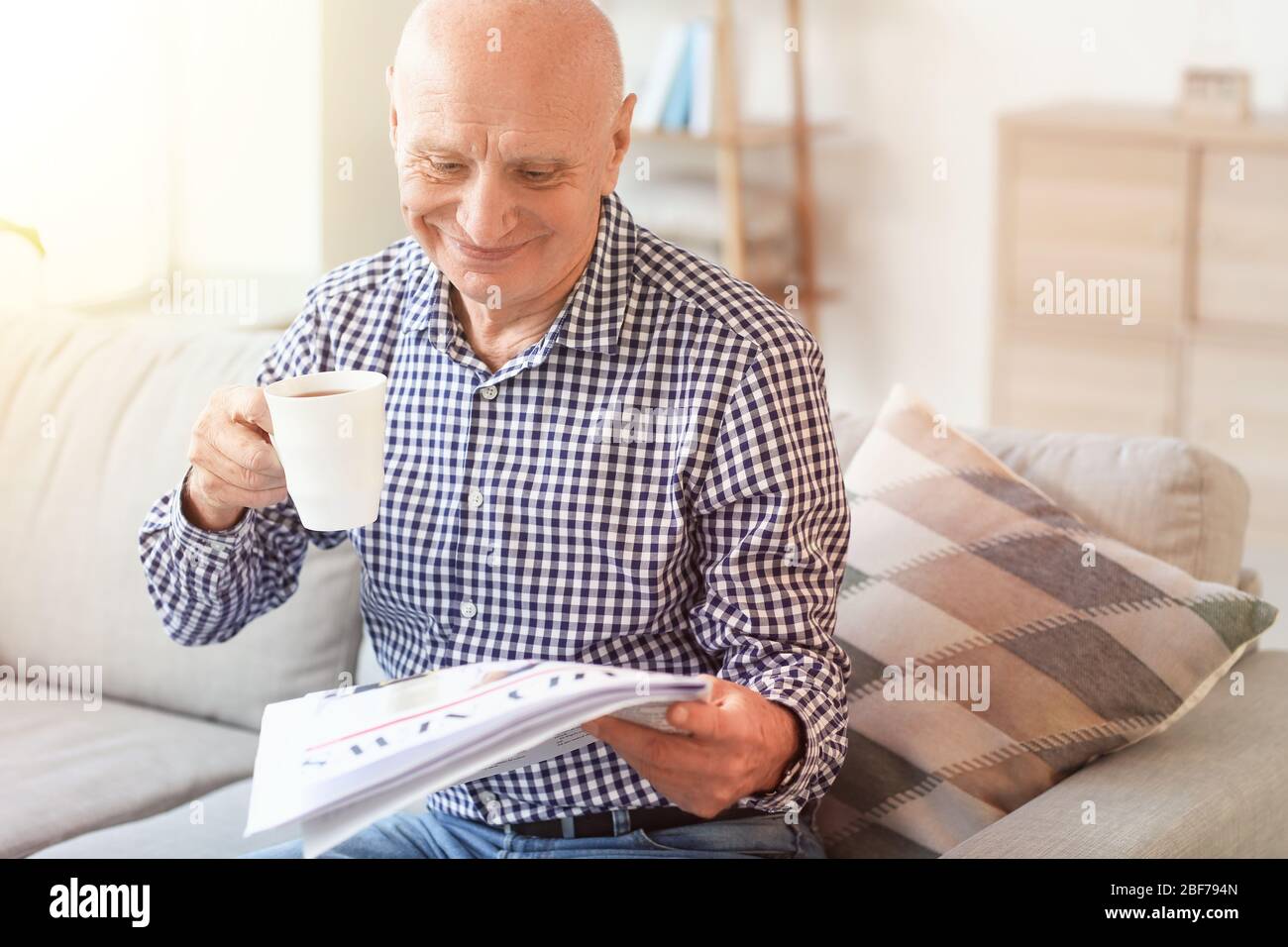 Uomo anziano che legge giornale a casa Foto Stock