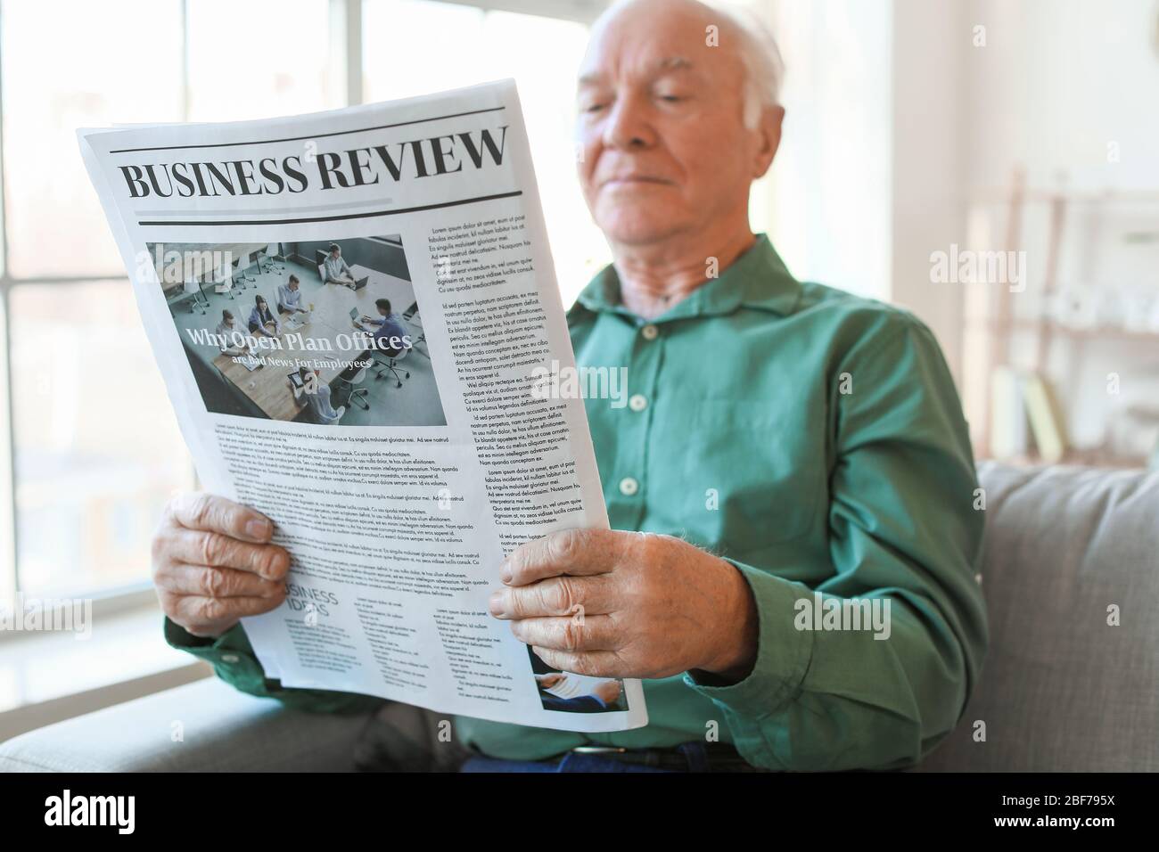 Uomo anziano che legge giornale a casa Foto Stock