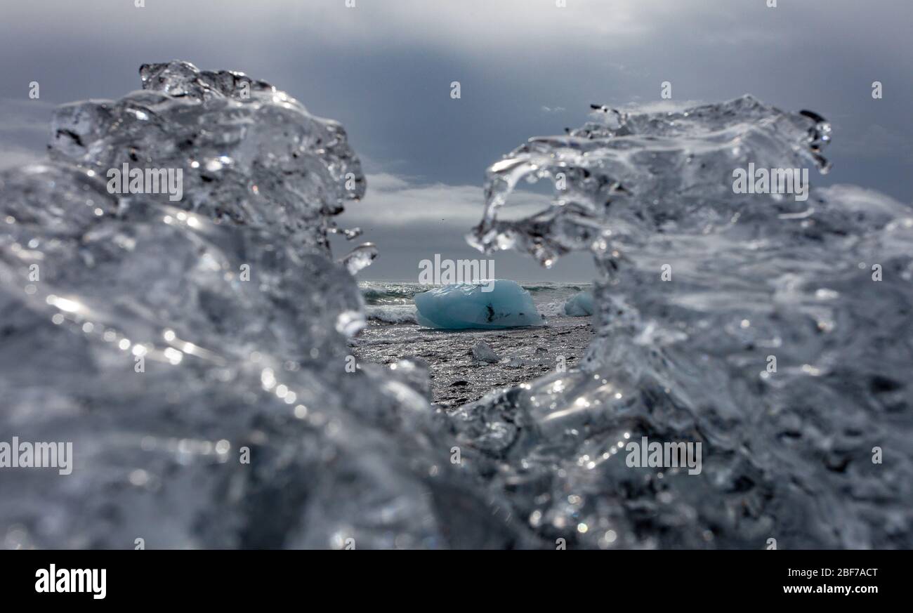 Un grande pezzo di ghiacciaio può essere visto attraverso il ghiaccio parzialmente fuso e intricato sulla spiaggia dei diamanti dell'Islanda (nota anche come Breiðamerkursandur o Fellsfjara). Foto Stock