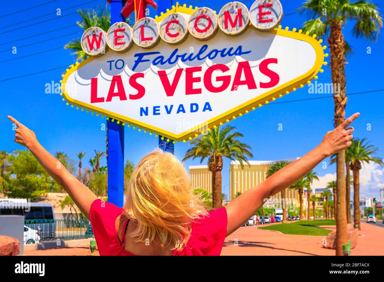 Donna spensierata con braccia sollevate al cartello Welcome to Fabulous Las Vegas Nevada Sign, famoso punto di riferimento sulla Las Vegas Strip all'ingresso della città. Felice Foto Stock