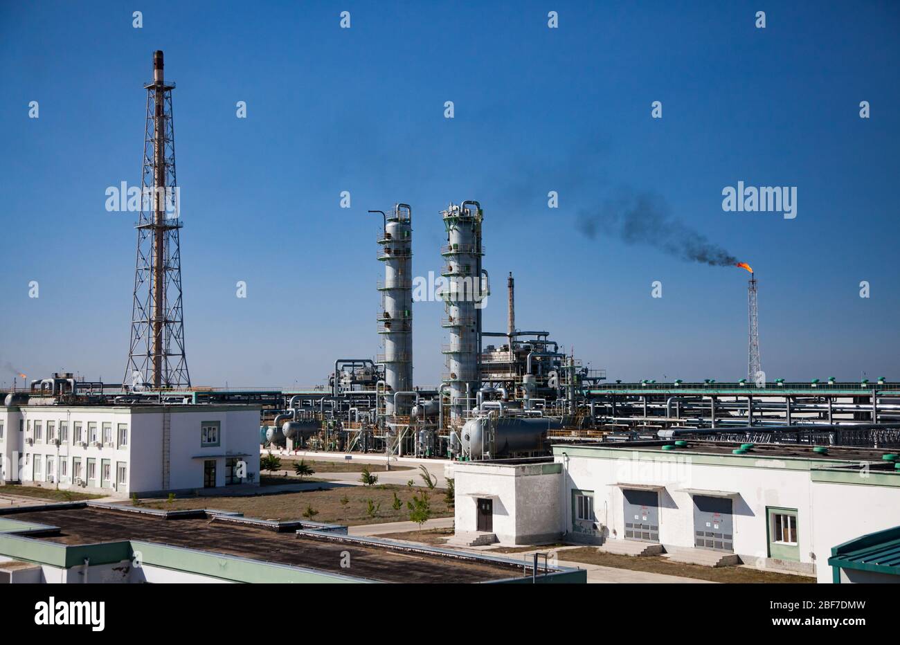 Vista della torre di comunicazione, delle torri di distillazione, della torcia a gas, delle condutture e degli edifici industriali contro il cielo azzurro. Raffineria di petrolio e gas p Foto Stock