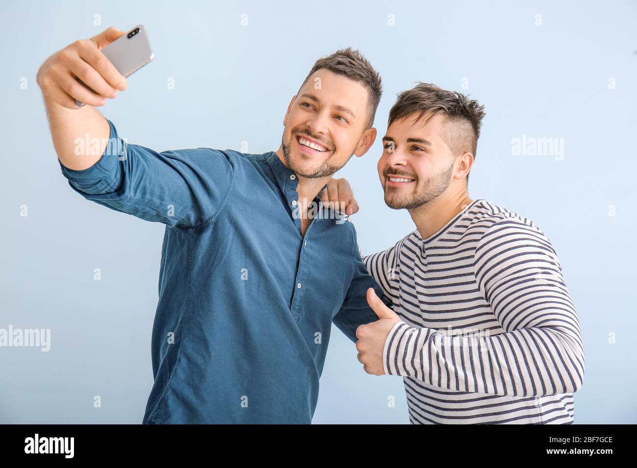 Ritratto di amici felici che prendono selfie su sfondo a colori Foto Stock