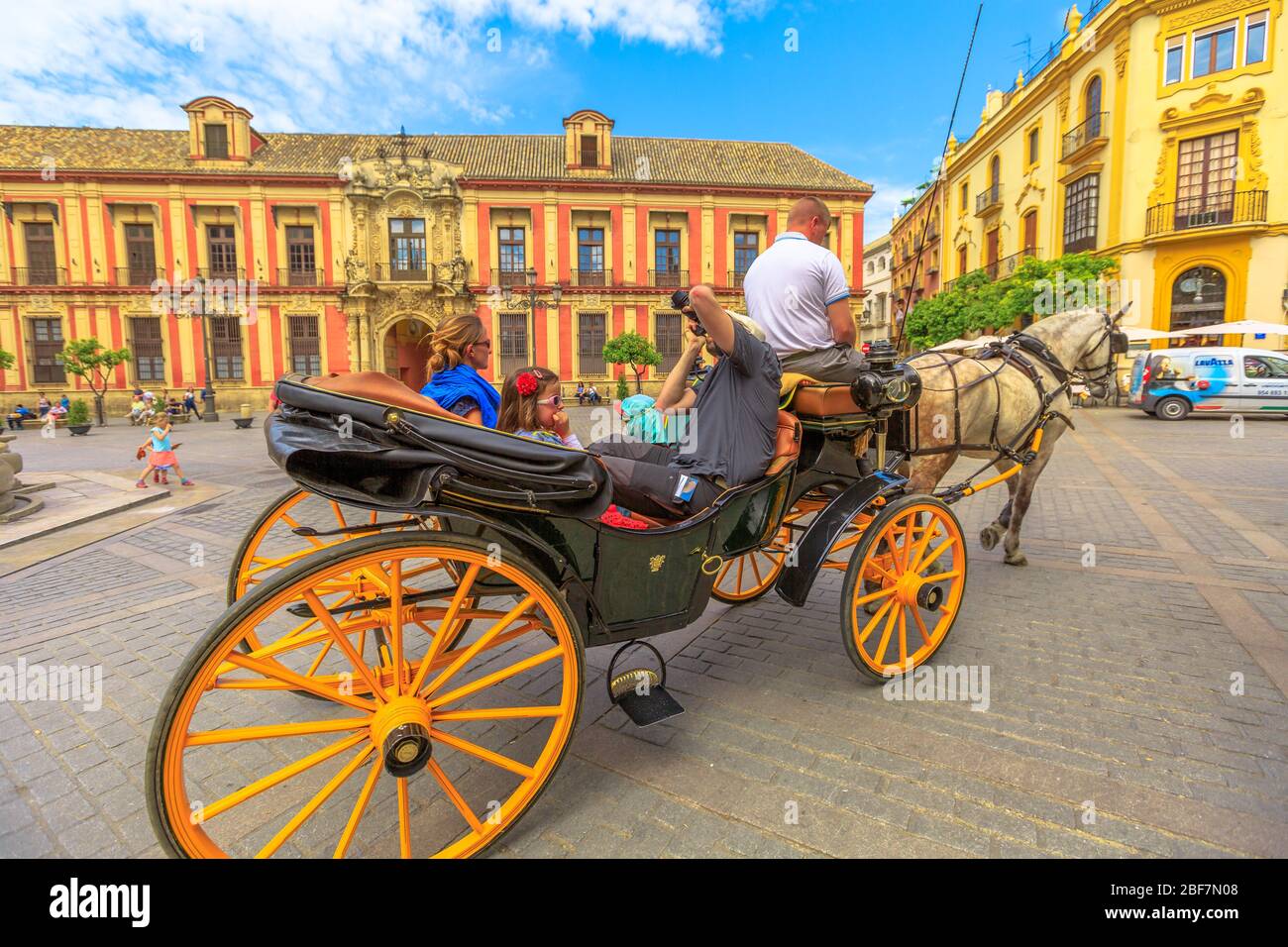 Siviglia, Andalusia, Spagna - 18 aprile 2016: Vista prospettica dei turisti facendo un giro in carrozza a cavallo in Plaza Virgen De Los Reyes piazza con Foto Stock