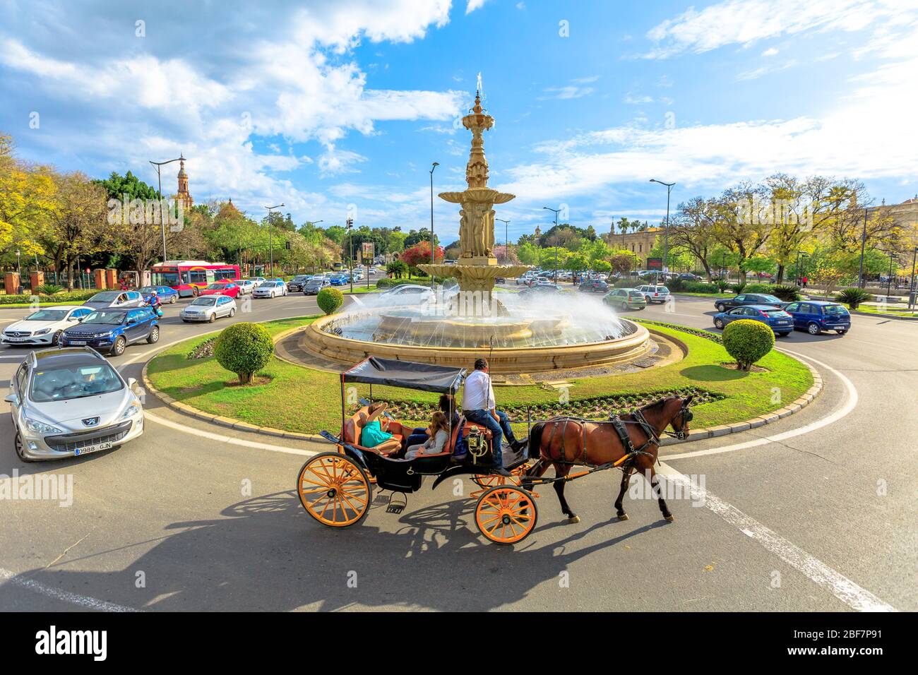 Siviglia, Andalusia, Spagna - 19 aprile 2016: Giro turistico della città in carrozza a cavallo intorno alla fontana in Plaza Don Juan de Austria. Paesaggio urbano da Foto Stock